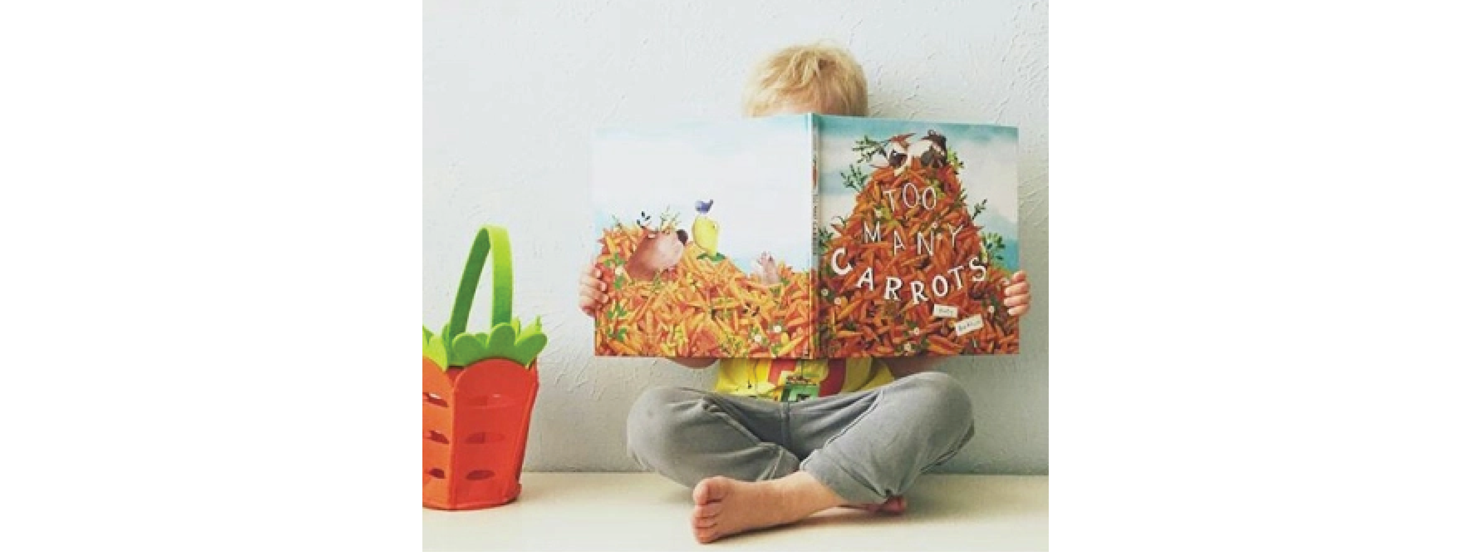 Child reads a hardback copy of Too Many Carrots